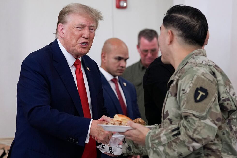 Republican presidential candidate and former President Donald Trump, left, helps serve food to...